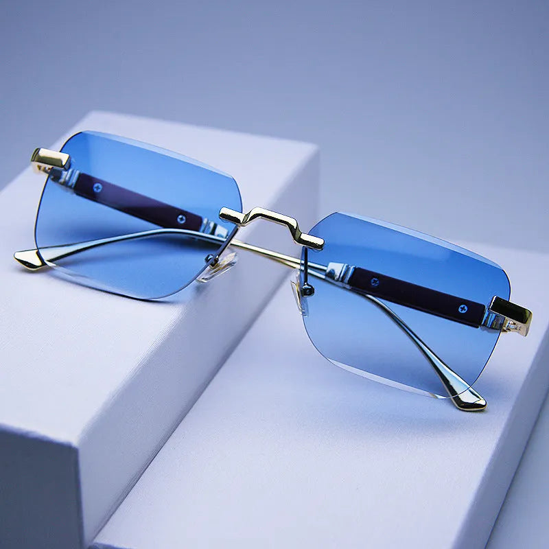 Frameless edge-cut sunglasses with gold frame, wood grain legs, and gradient grey lenses on a neutral background