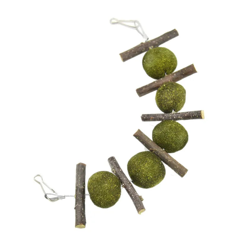 Natural grass balls and apple branches hanging chew toys for small pets on a cage bar