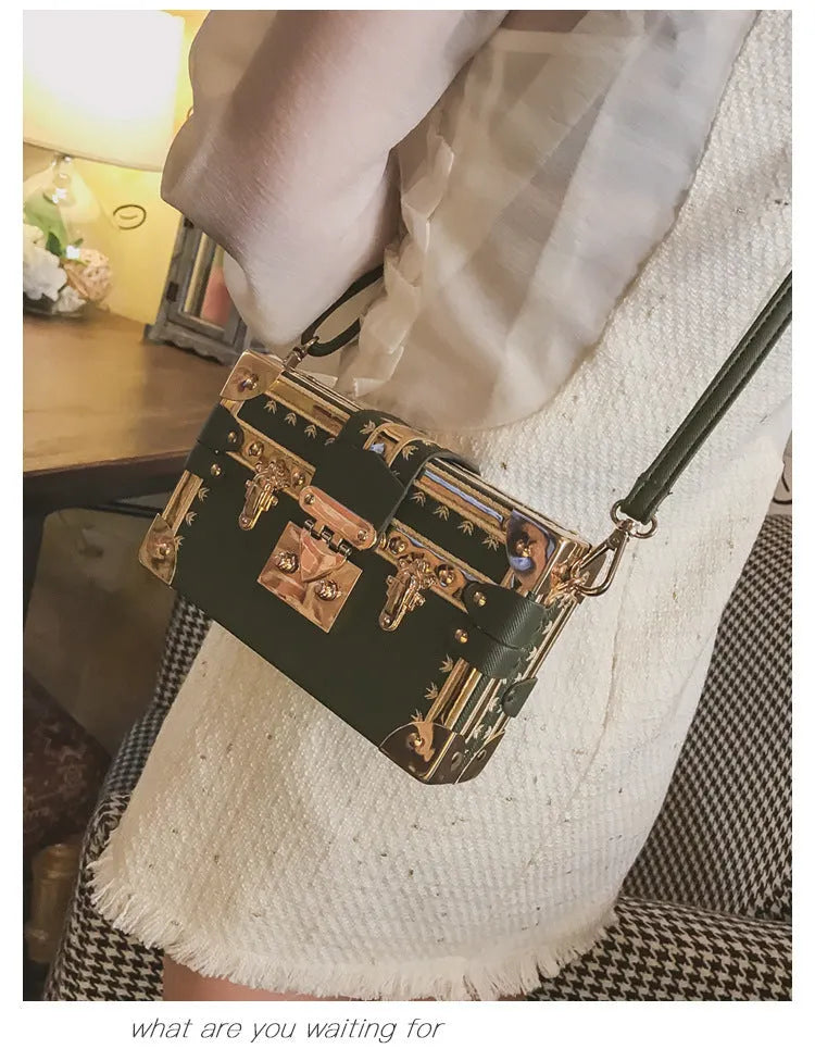 Black or green women's hard-shell flap-over shoulder bag with single adjustable strap