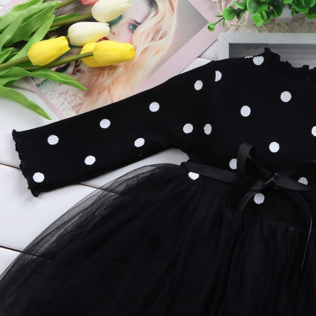 Baby girl in a long sleeve black tutu lace dress for a christening or birthday party.