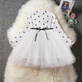 Baby girl in a long sleeve black tutu lace dress for a christening or birthday party.