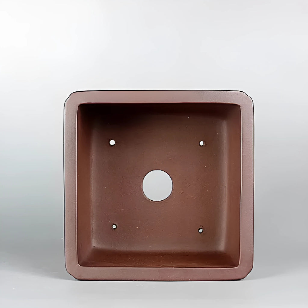 Handmade brown antique purple clay flower pot for indoor plants on a desktop.