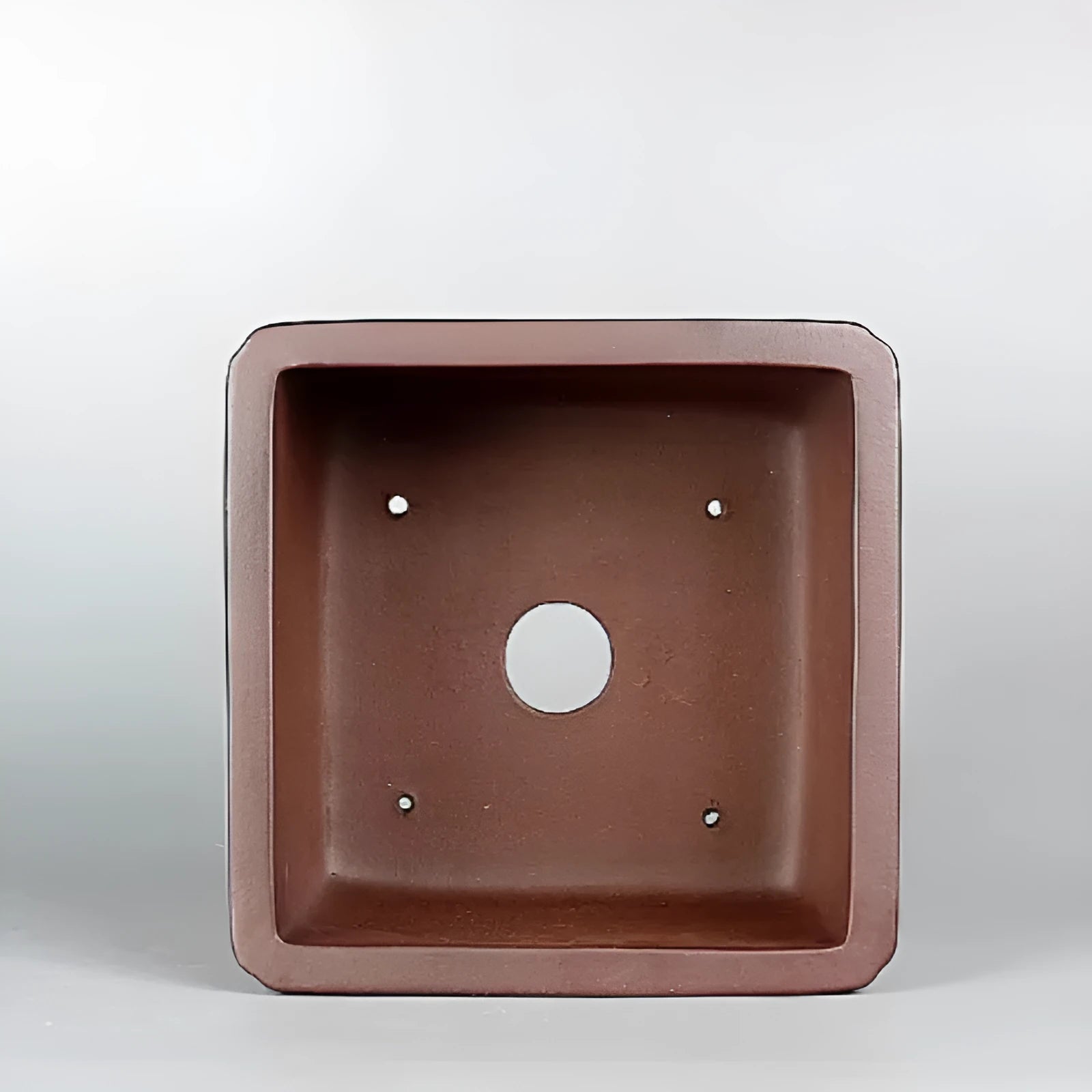 Handmade brown antique purple clay flower pot for indoor plants on a desktop.