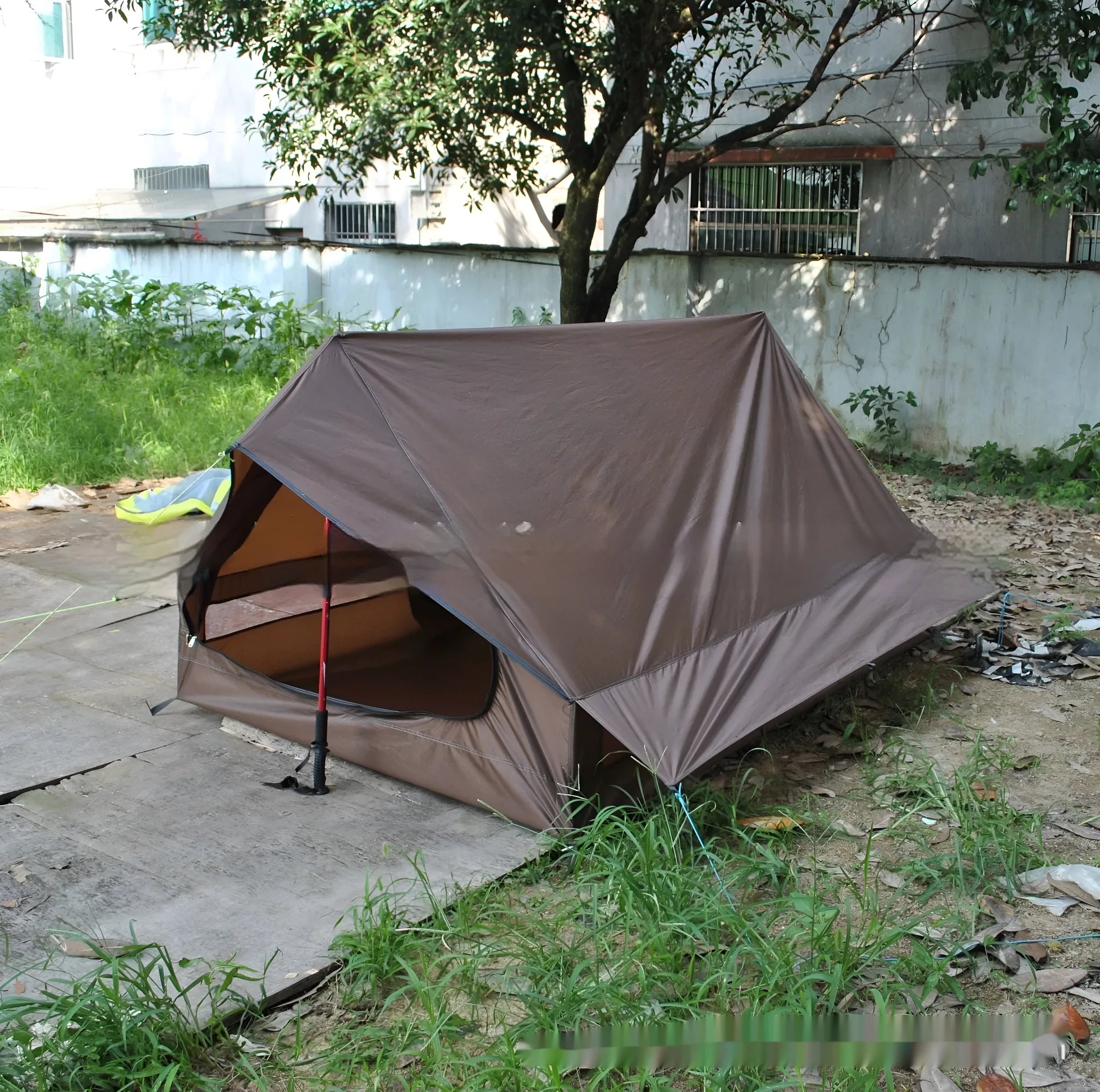 Brown or white A-frame pole-free cabin tent erected with hiking cane supports