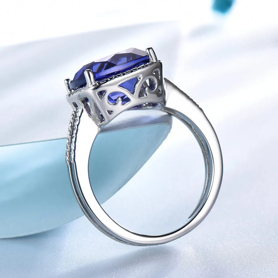 Blue Tanzanite stone set in a sterling silver 925 ring for women, shown on a finger.