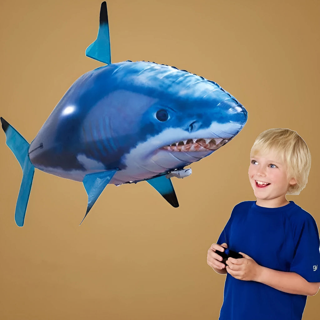 Large remote control shark-shaped helium balloon toy floating indoors with a remote.