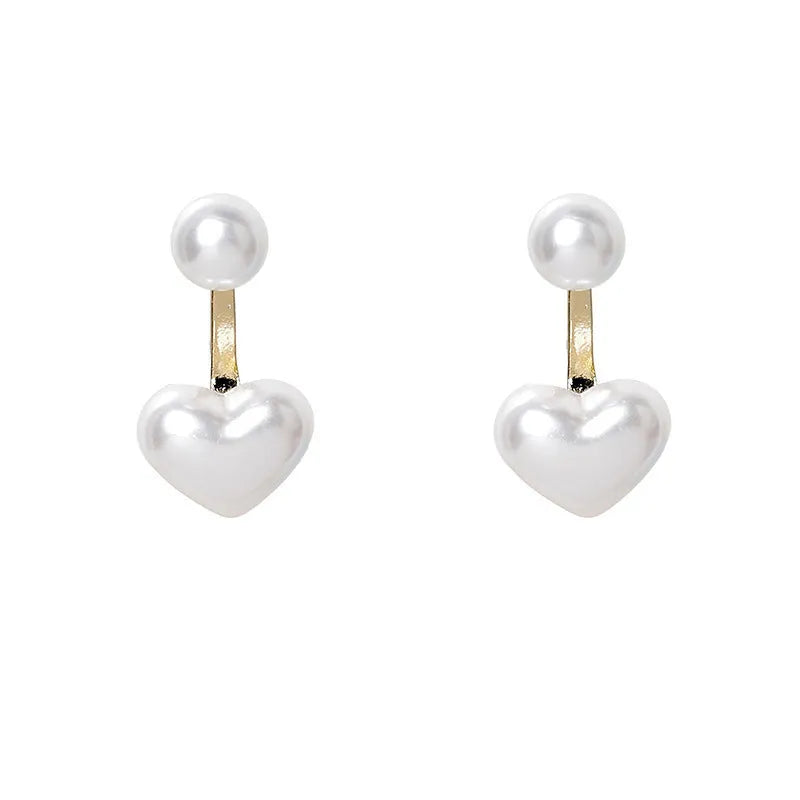 Close-up of women's silver-toned heart-shaped stud earrings with a central inlaid artificial pearl or gemstone.