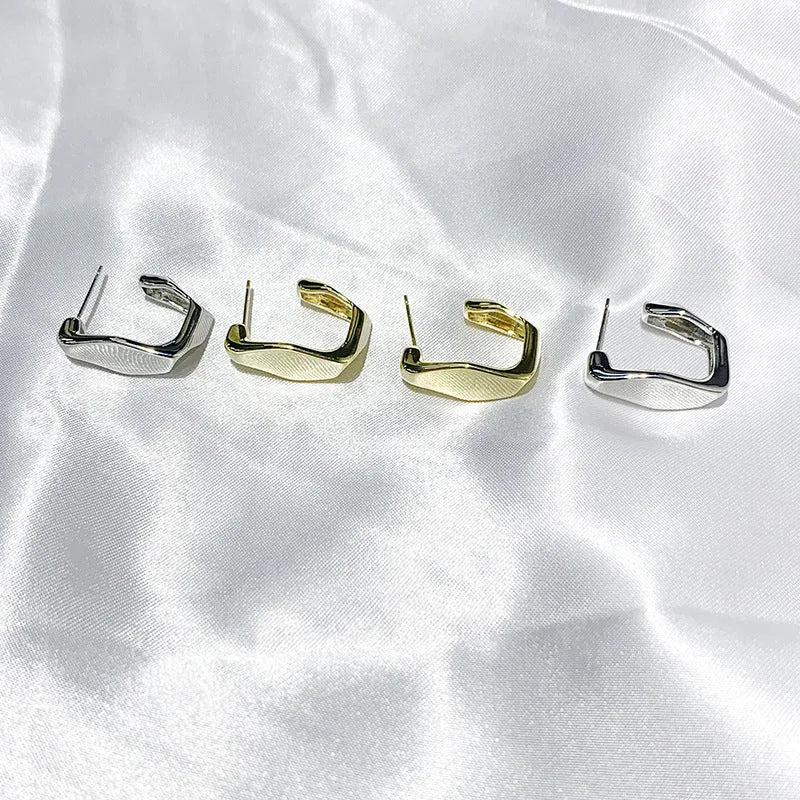 Irregular C-shaped metal stud earrings in Gold finish, minimalist design for everyday wear.