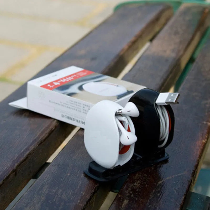 Automatic earphone cable retractor winder in a compact plastic storage box.