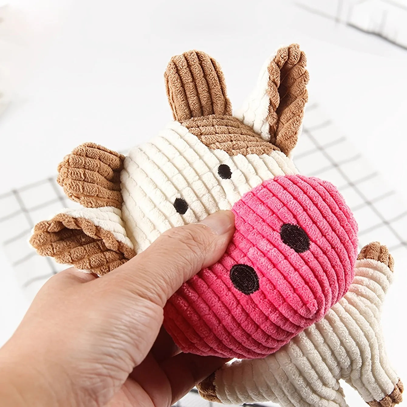 Animal-shaped plush dog chew toy with squeaker in assorted colours including blue, brown, and cow print.