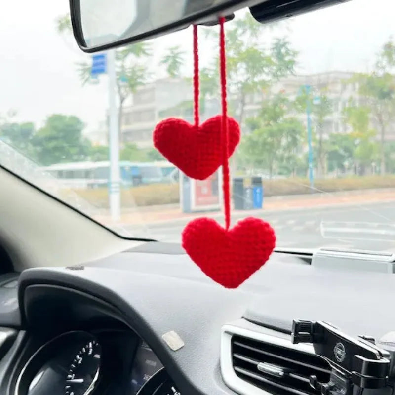Green and white knitted wool car plant decoration hanging from a rope.