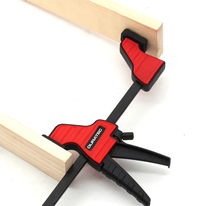 Black plastic woodworking clamp with quick-adjust key and soft rubber protective grip.