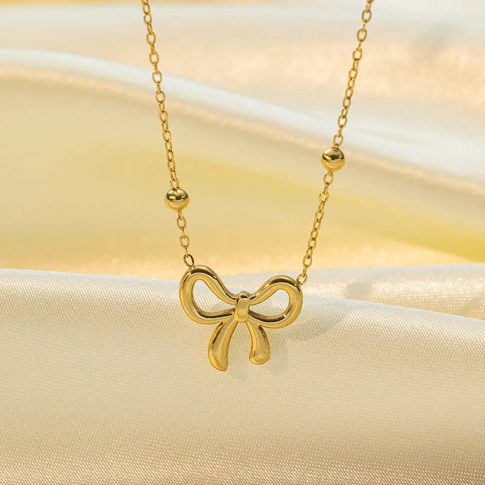 Gold bow necklace with adjustable cross chain on women's neck