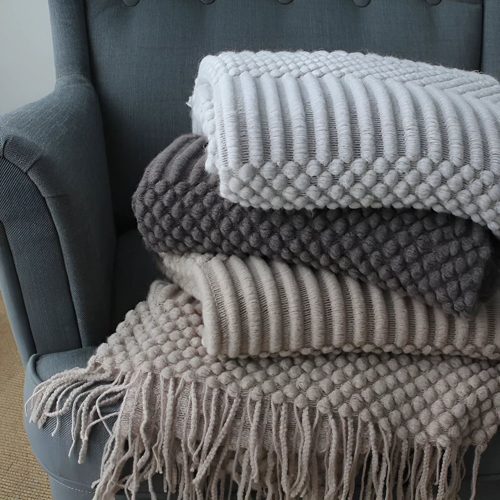 Small light grey polyester throw blanket folded on a sofa