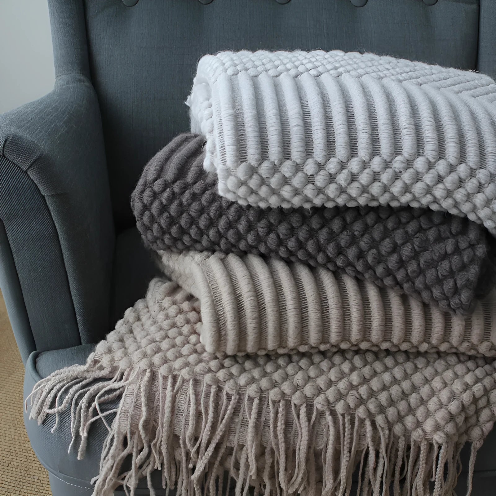 Small light grey polyester throw blanket folded on a sofa