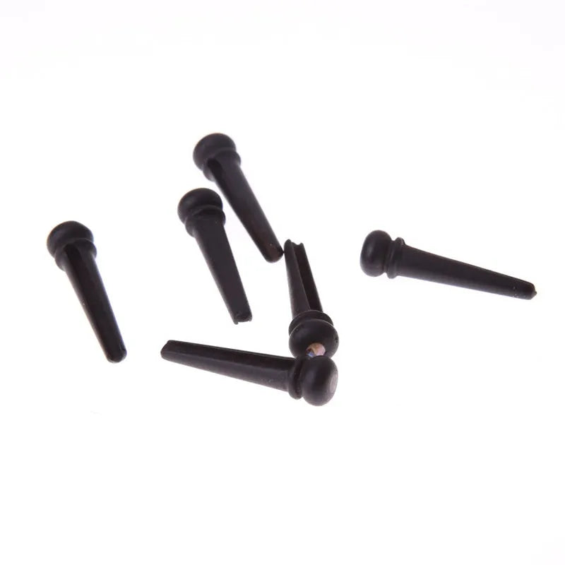 Six matt black ebony folk guitar bridge pins with 5.3mm bayonet diameter on a plain background.