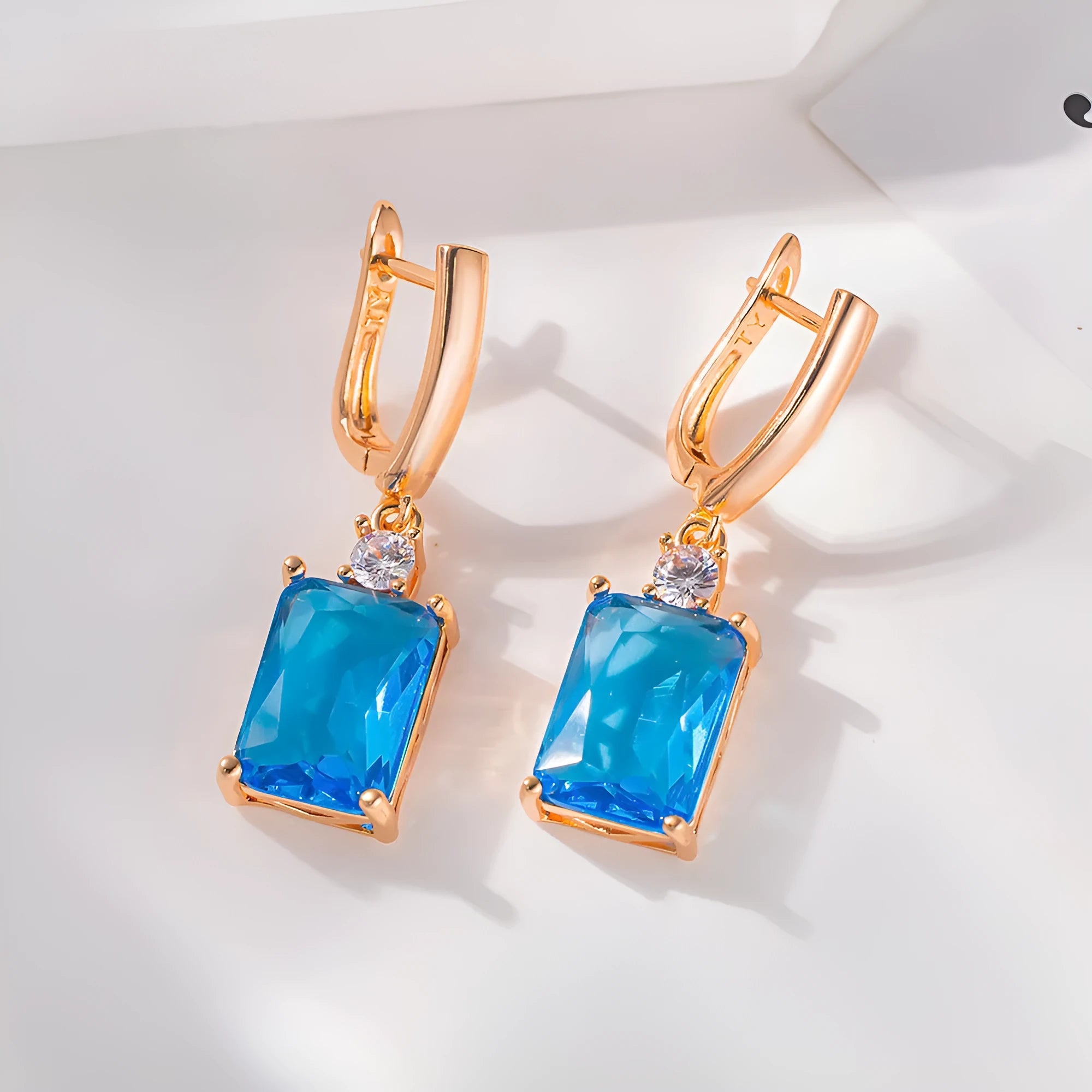 A pair of square-shaped gold and silver electroplated copper earrings on a flat surface.
