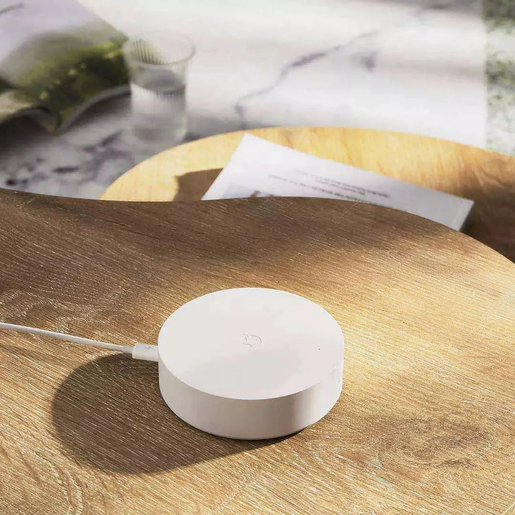White circular Xiaomijia smart home gateway with UK plug for wall mounting.