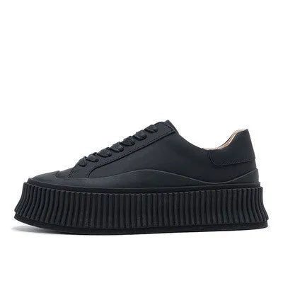 Women's black suede platform lace-up trainers with chunky rubber sole and cross-binding detail on the upper.