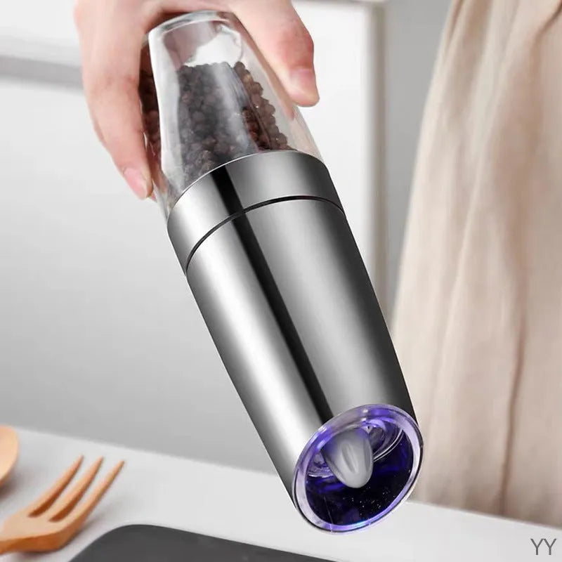 Electric gravity pepper grinder with clear acrylic body and blue LED light on a kitchen countertop