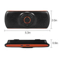 Orange plastic Bluetooth hands-free car speaker mounted on a sun visor for wireless phone calls and music.