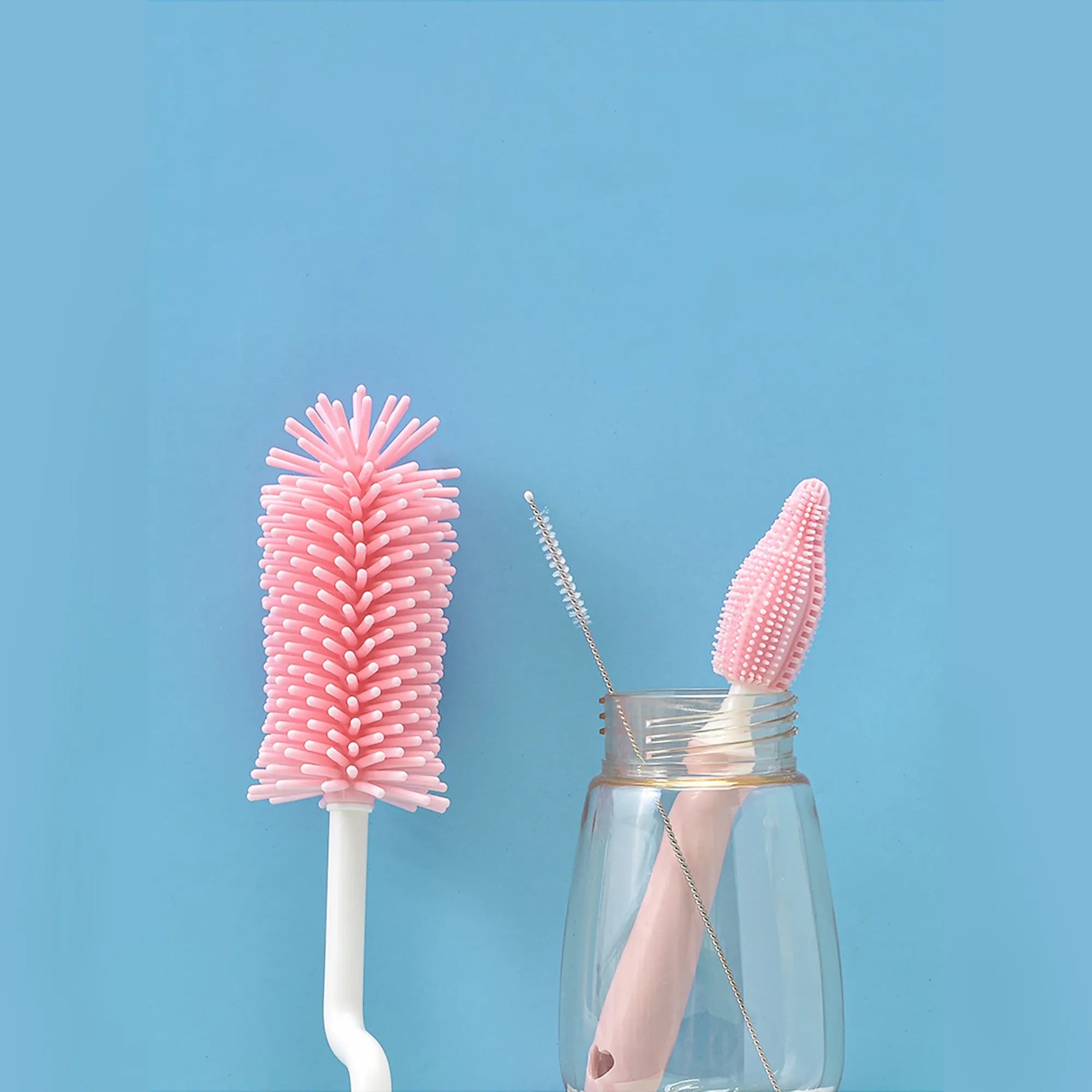 Silicone baby bottle cleaning brush and separate straw cleaner in pink, blue, and yellow colours.
