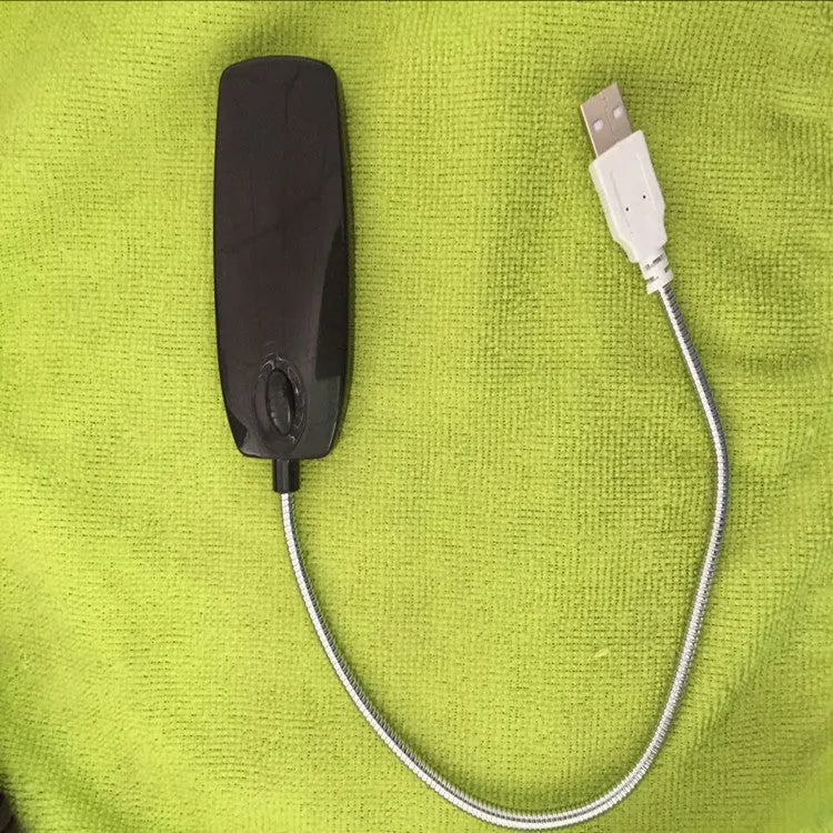 Black flexible USB gooseneck LED lamp bent over a laptop keyboard.