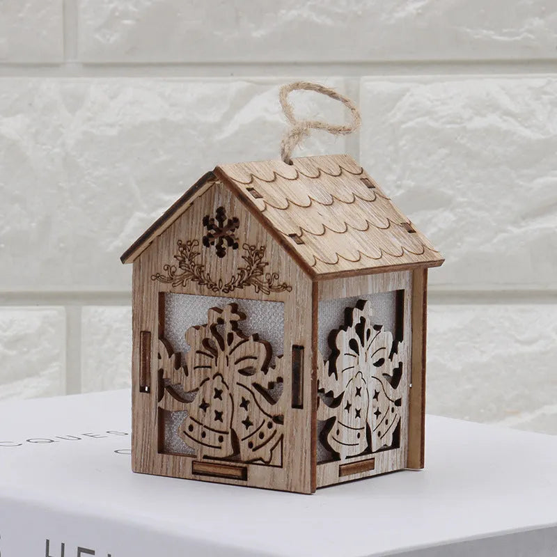Three handcrafted wooden Christmas house decorations on a rustic table: a log bell, a painted old man cottage, and a snowman house.