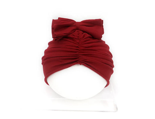 Soft acrylic knitted baby girl turban hat in a solid colour, shown on an infant.