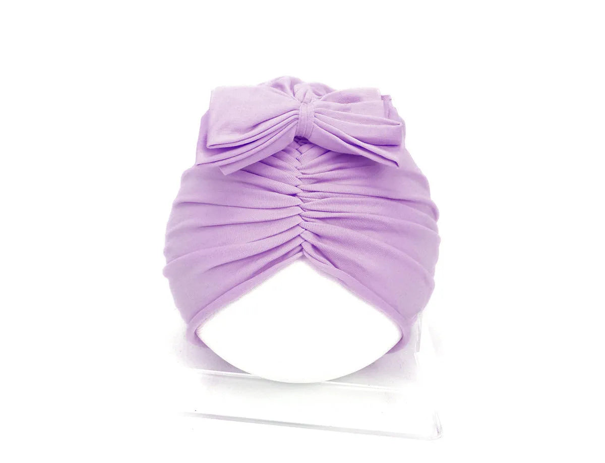 Soft acrylic knitted baby girl turban hat in a solid colour, shown on an infant.