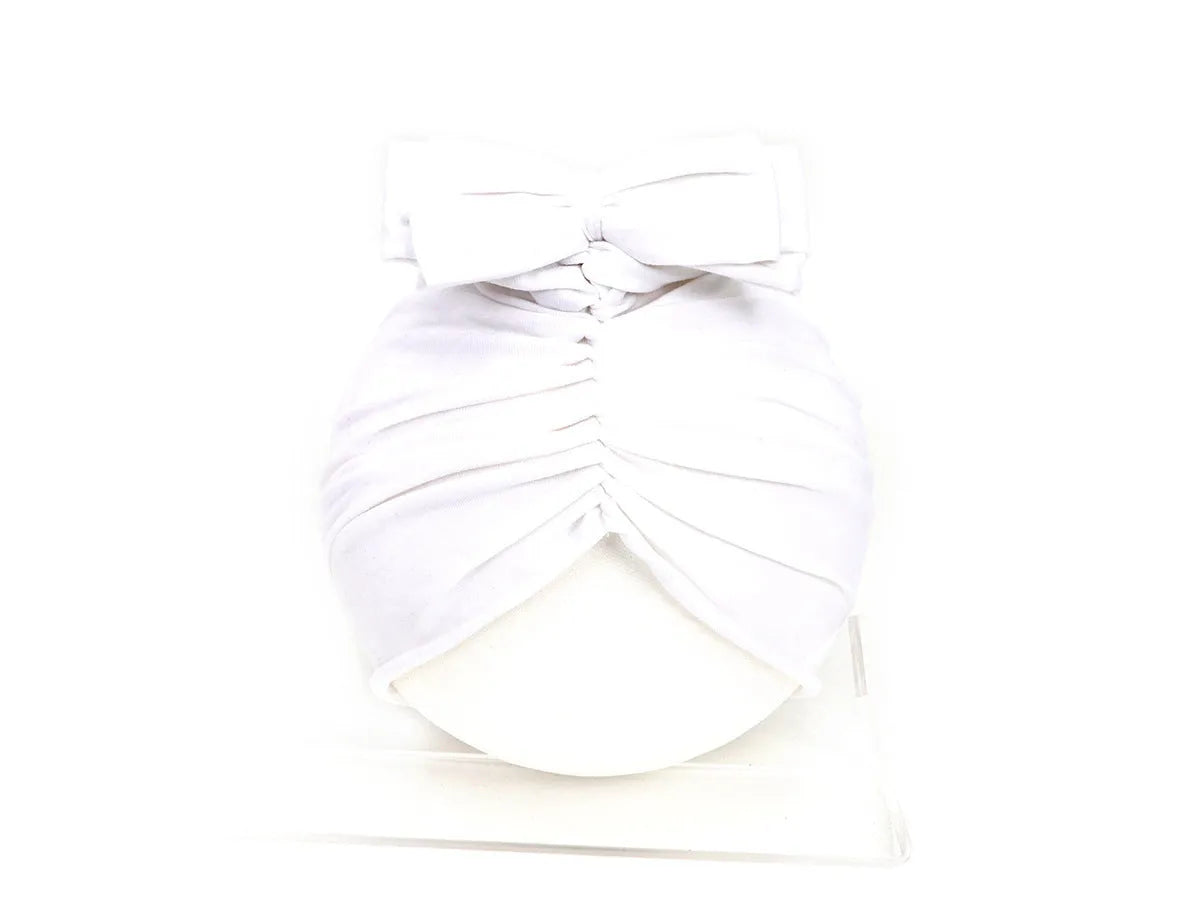 Soft acrylic knitted baby girl turban hat in a solid colour, shown on an infant.