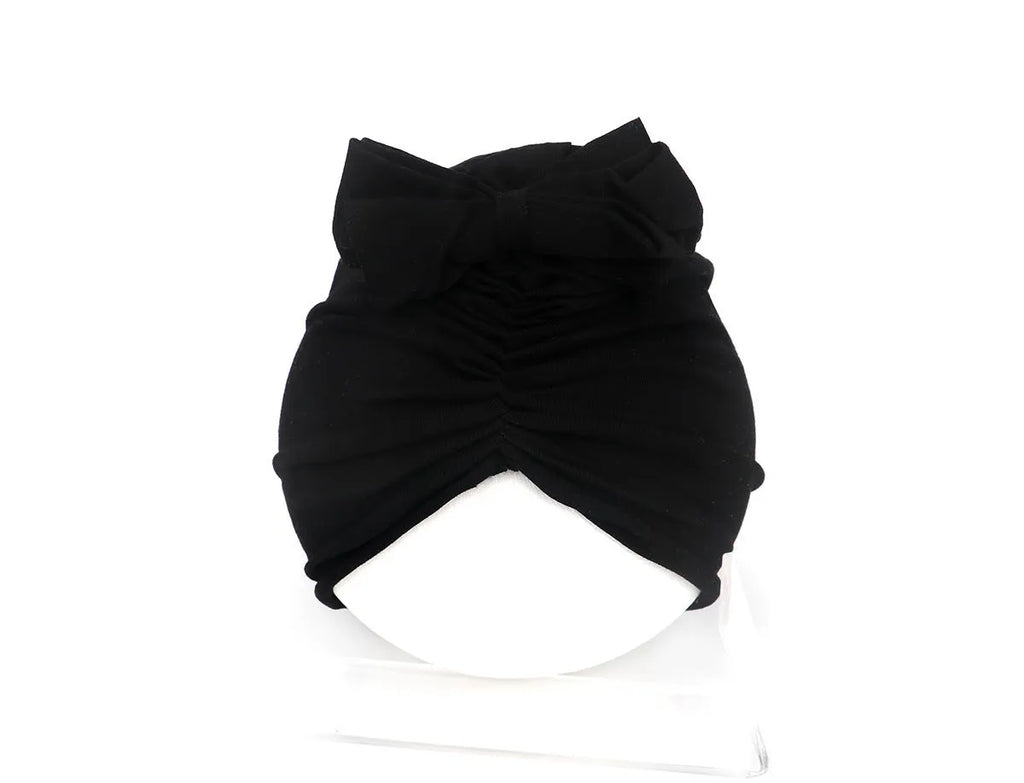 Soft acrylic knitted baby girl turban hat in a solid colour, shown on an infant.