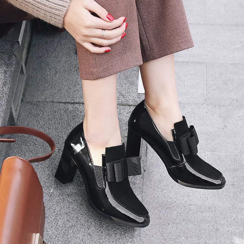 Black patent leather women's high-heel shoes with a thick heel and square toe.