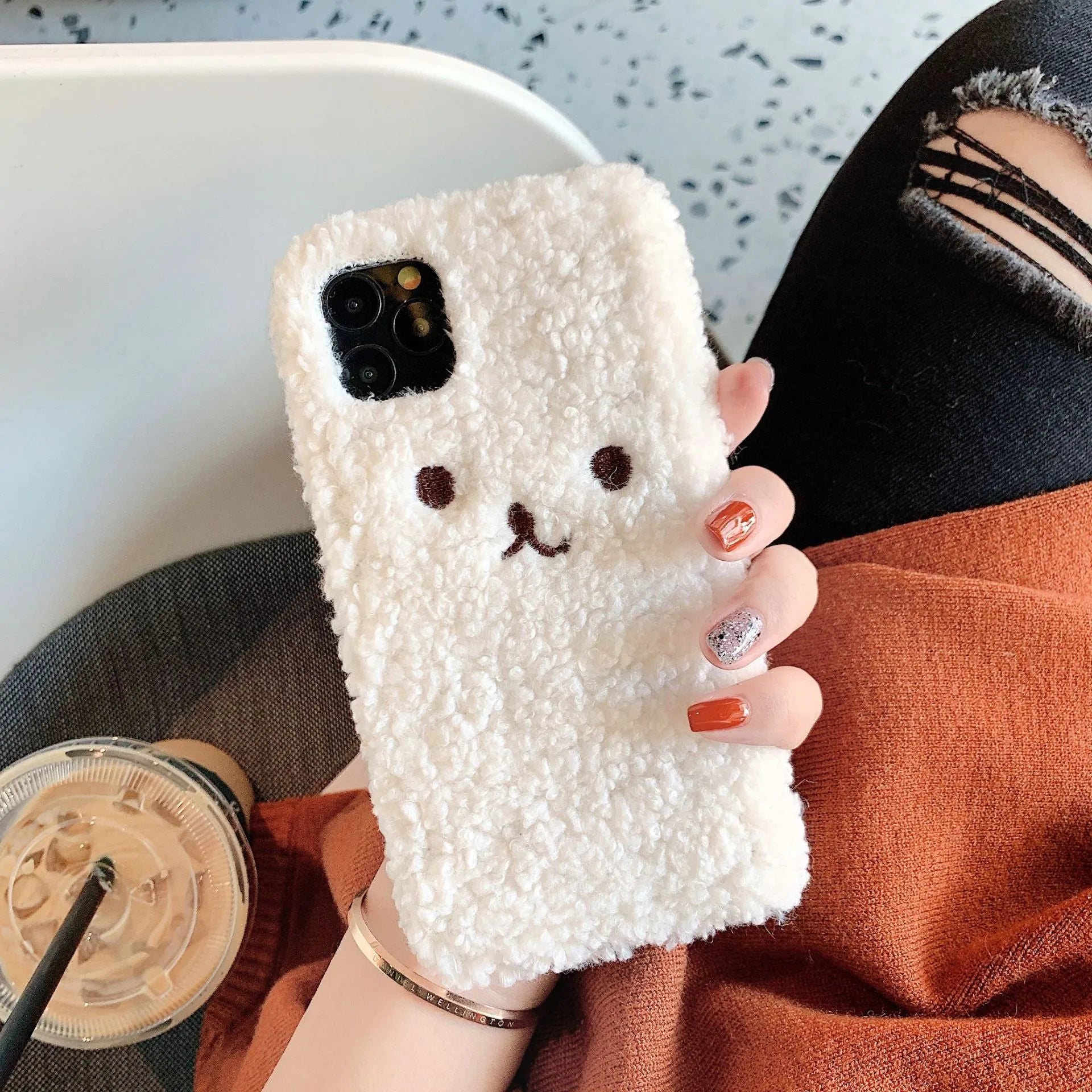 Brown TPU iPhone case with a soft embroidered plush cartoon bear face on the back.