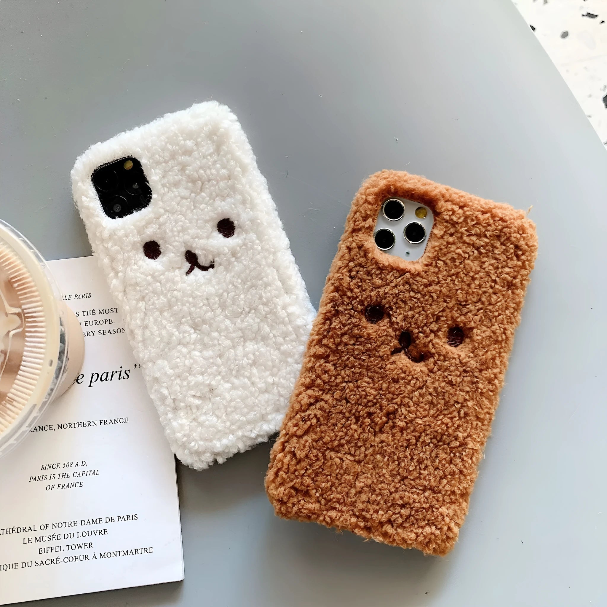 Brown TPU iPhone case with a soft embroidered plush cartoon bear face on the back.