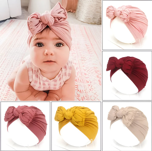 Soft acrylic knitted baby girl turban hat in a solid colour, shown on an infant.