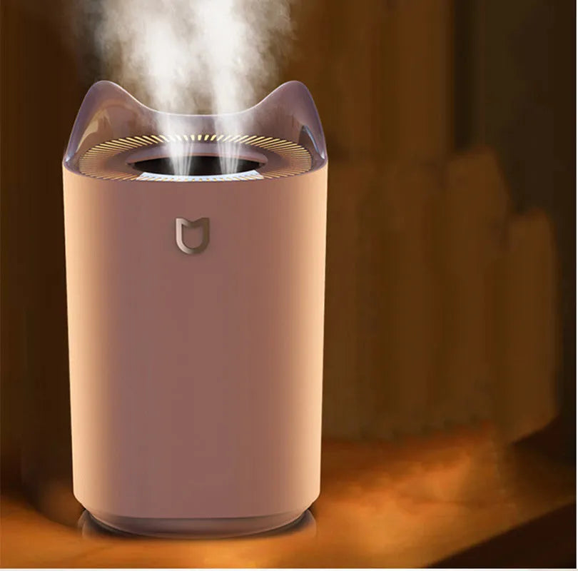 Coral pink USB humidifier with three mist outlets and visible water tank on a bedside table