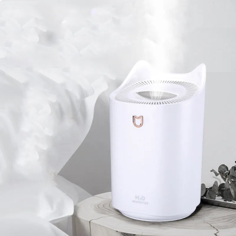 Coral pink USB humidifier with three mist outlets and visible water tank on a bedside table