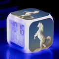 Square creative alarm clock with LED display and colour-changing light on a bedside table