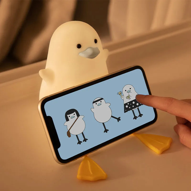 Little Gull rechargeable silicone night light in blue mouth on a bedside table