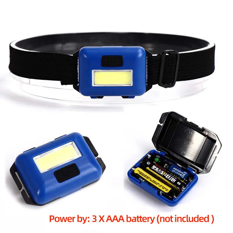 Mini black LED headlamp with adjustable strap showing strong light beam, held in hand.