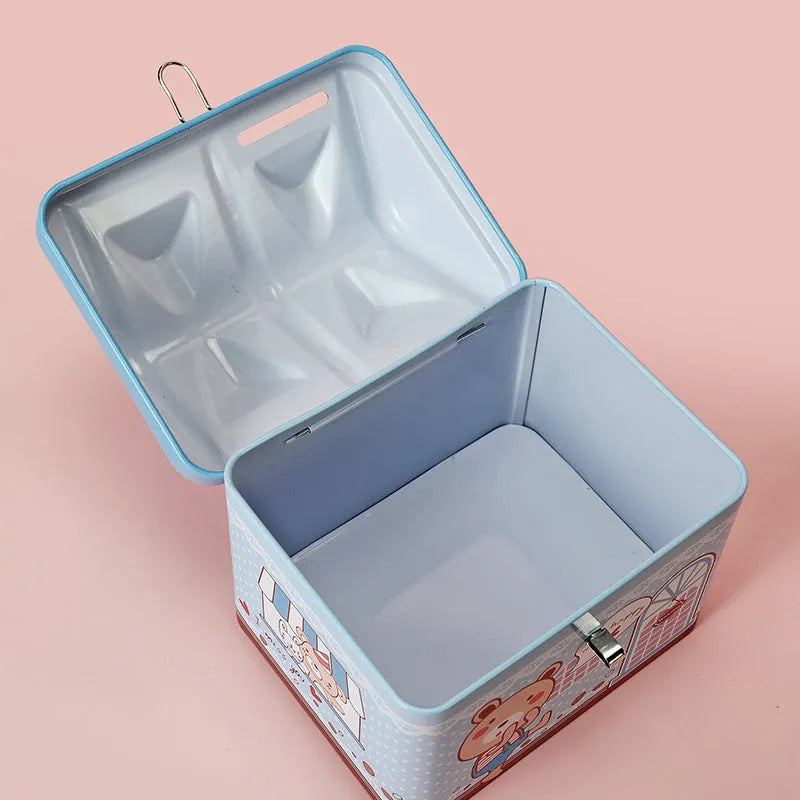 Blue house-shaped tinplate piggy bank on a wooden desk surface.