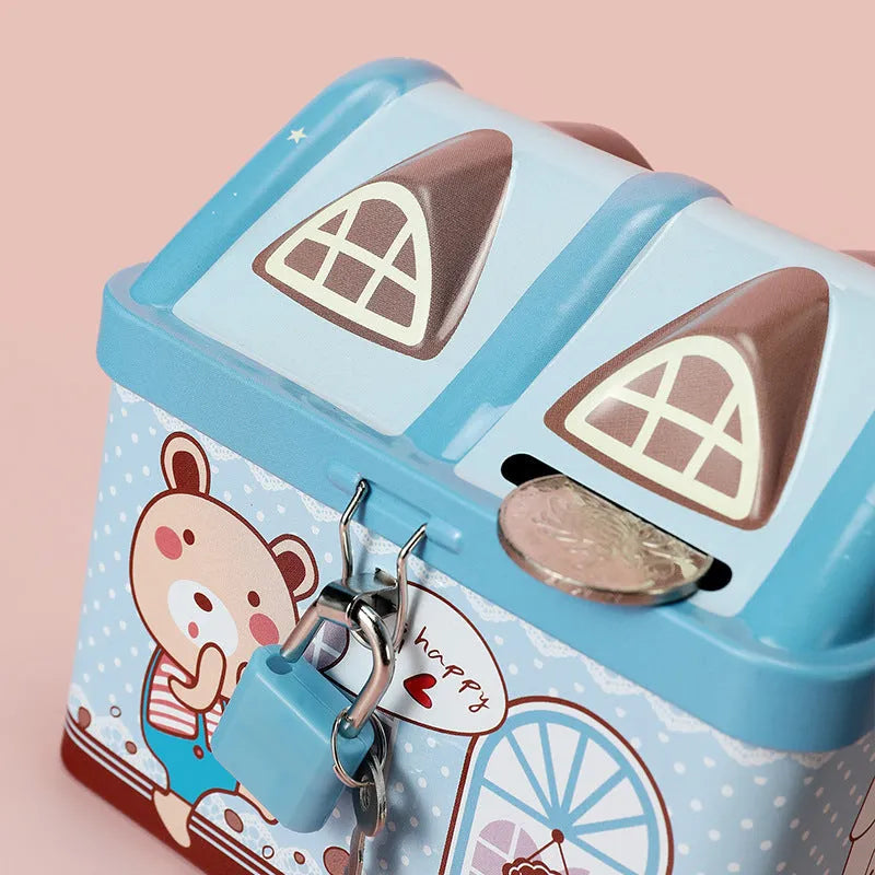 Blue house-shaped tinplate piggy bank on a wooden desk surface.