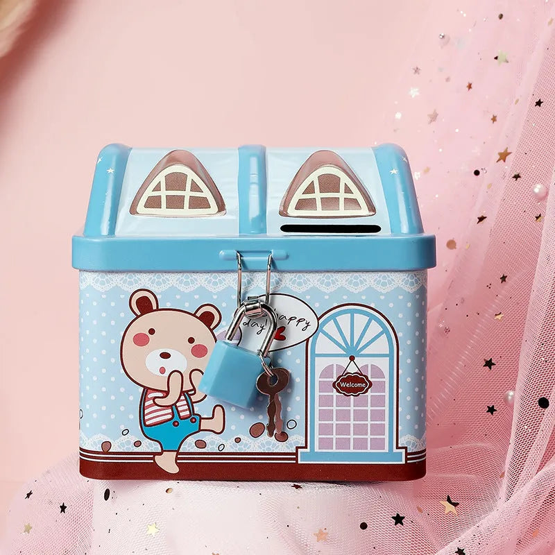 Blue house-shaped tinplate piggy bank on a wooden desk surface.