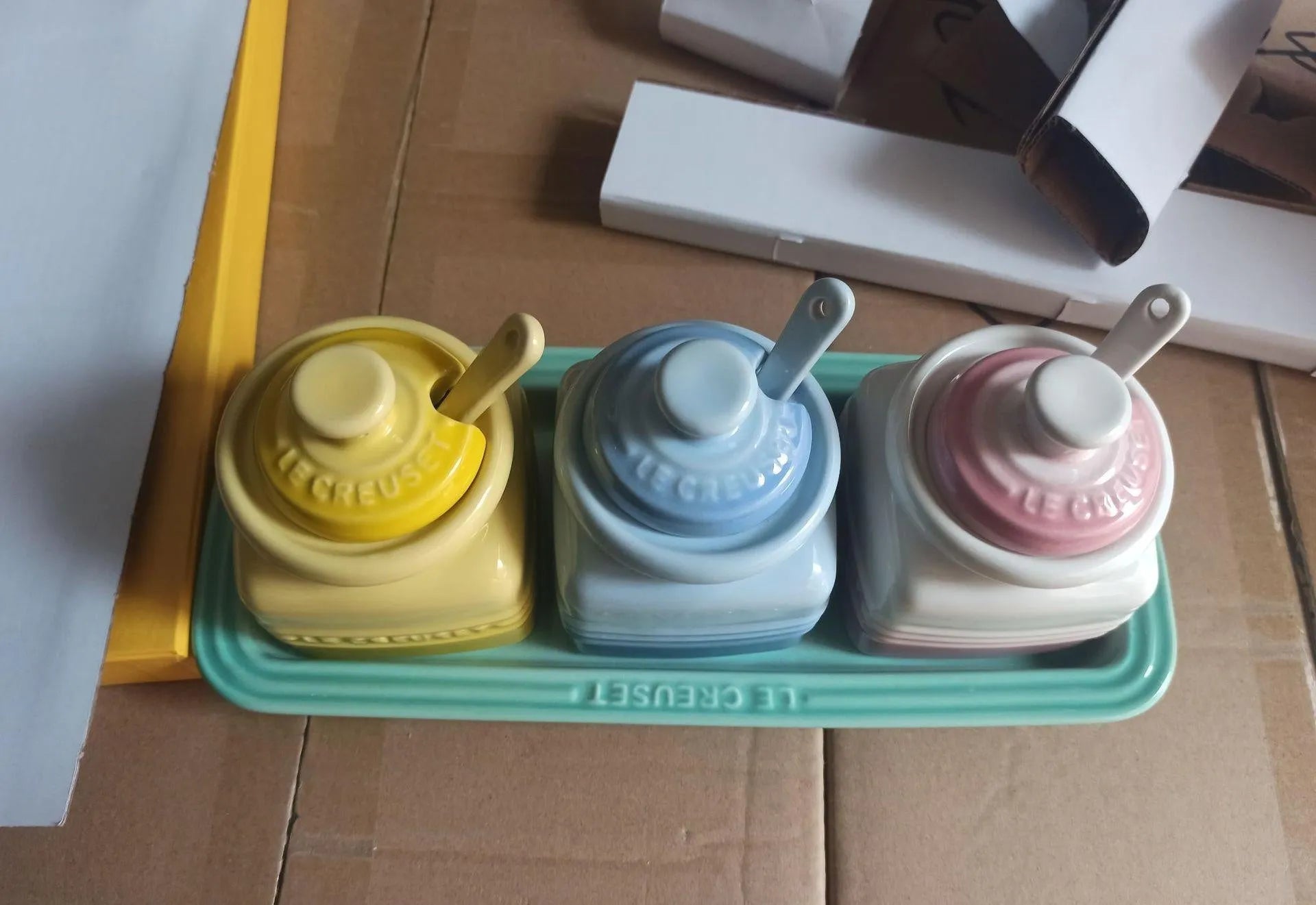 Ceramic seasoning jar set with three pots and spoons on a kitchen countertop