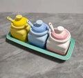 Ceramic seasoning jar set with three pots and spoons on a kitchen countertop