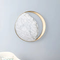 Round marble and copper LED wall lamp with eclipse design, 25 cm diameter, on a textured wall