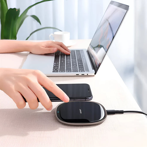 Black 15W Qi wireless charging pad with glass top and zinc alloy base on a desk.