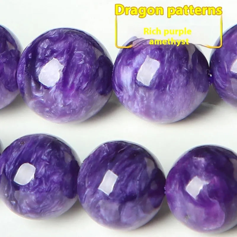 Natural transparent charoite crystal bead bracelet with platinum clasp on a wrist, showing violet and black swirled patterns.