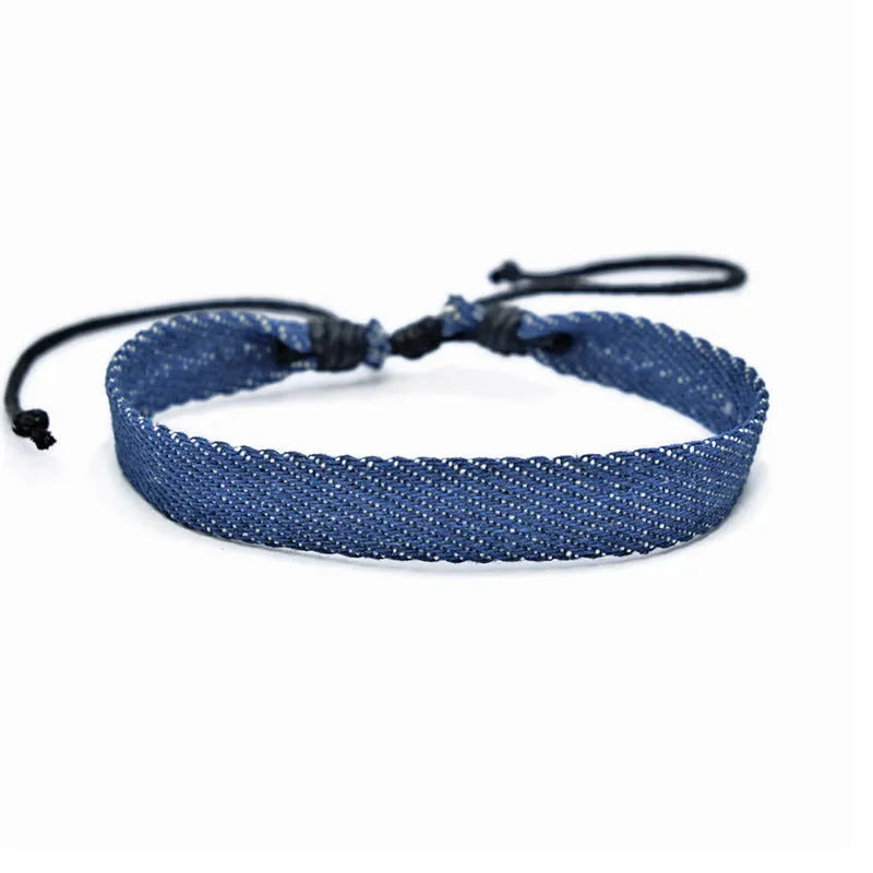 Handmade denim fabric bracelet carrying strap in national style on wrist, showing charm attachment point.
